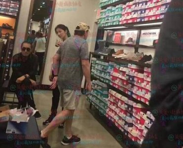 ​张艺谋陪娇妻购物 翘着二郎腿等着妻子陈婷捧着商品排队结账